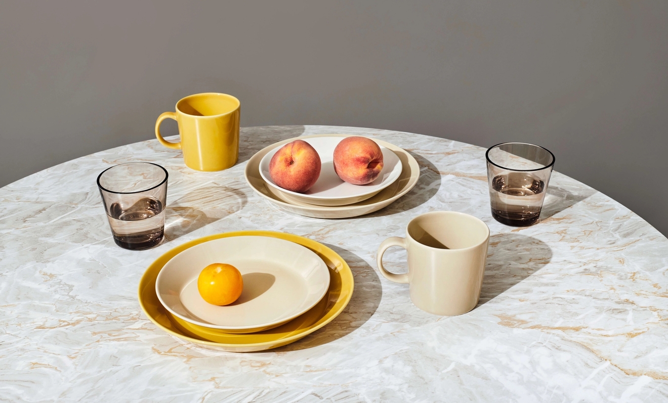 Iittala lautaset erikokoiset teema lautaset väreissä keltainen ja kerma pyöreällä pöydällä