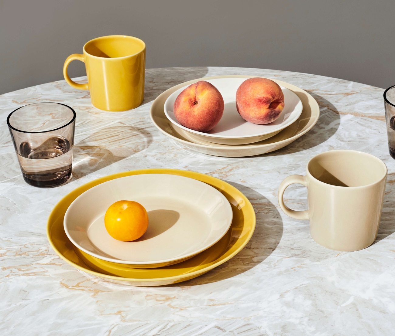 Iittala lautaset erikokoiset teema lautaset väreissä keltainen ja kerma pyöreällä pöydällä