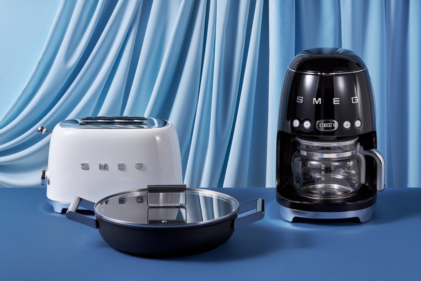 Smeg kaffebryggare svart och blå bakgrund av draperat tyg