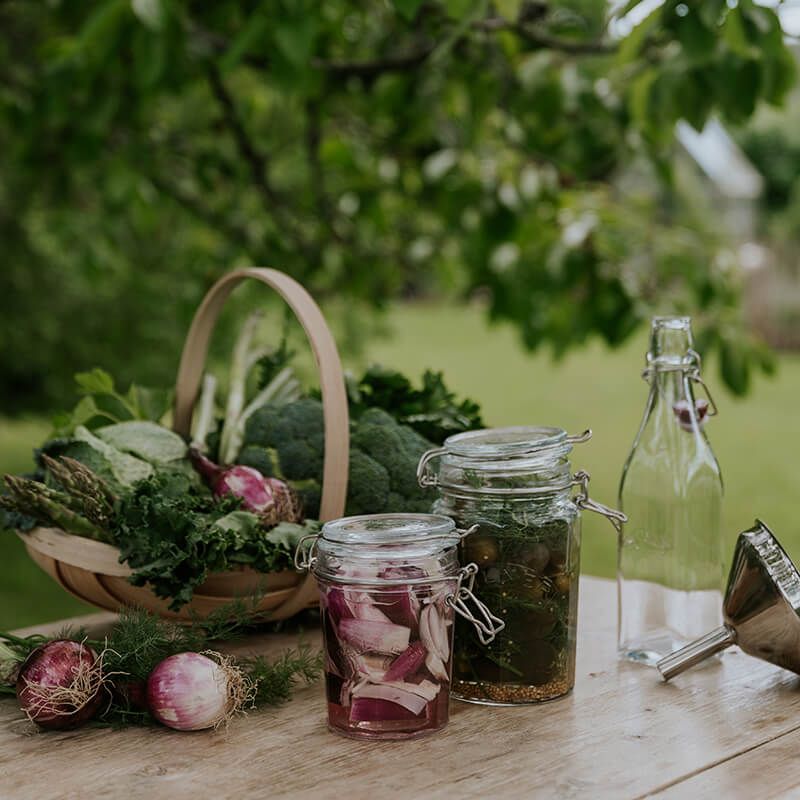 Skördade grönsaker i en korg på ett bord utomhus
