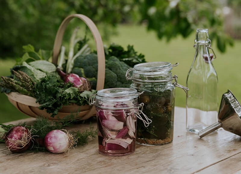 Skördade grönsaker i en korg på ett bord utomhus