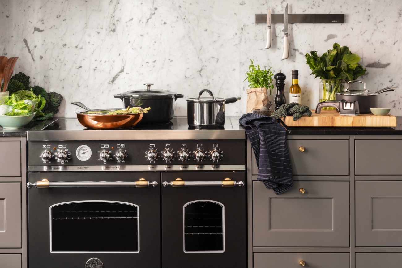 Anders Petter kastruller på en stor spis i ett lyxigt grått kök