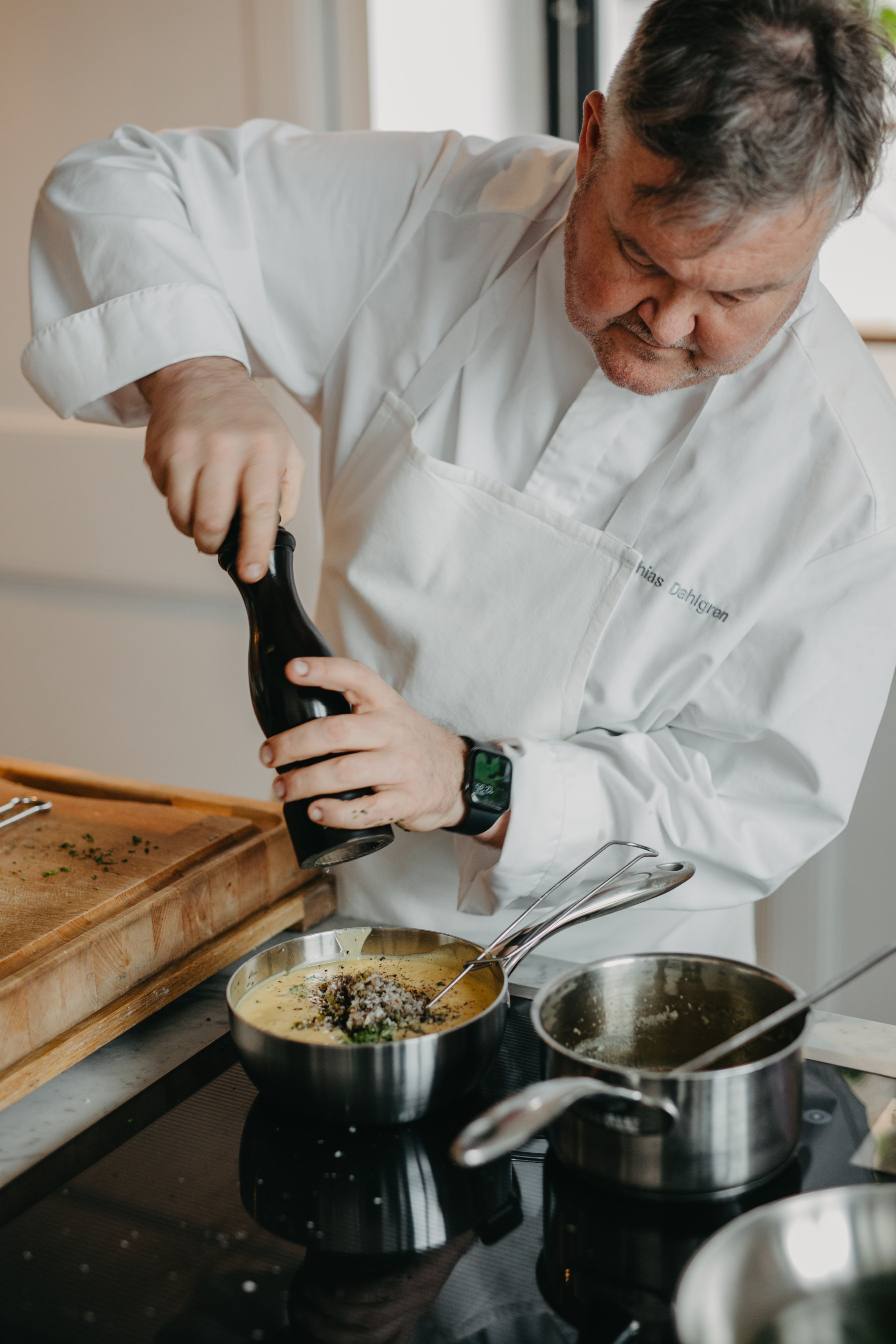 Kocken Mathias Dahlgren maler en pepparkvarn i en gryta på spisen.