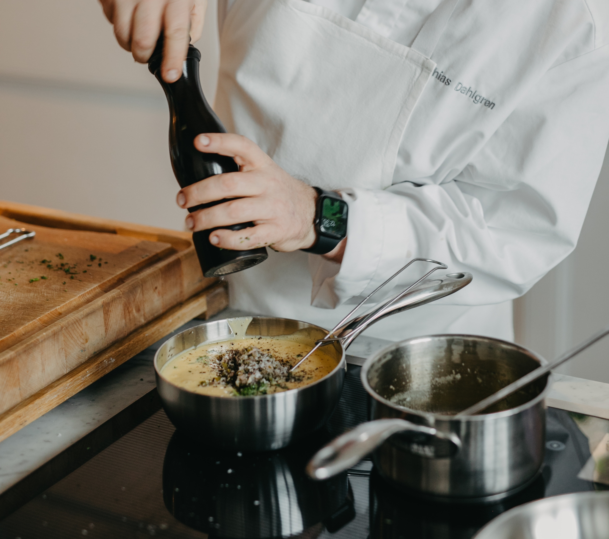 Kocken Mathias Dahlgren maler en pepparkvarn i en gryta på spisen.