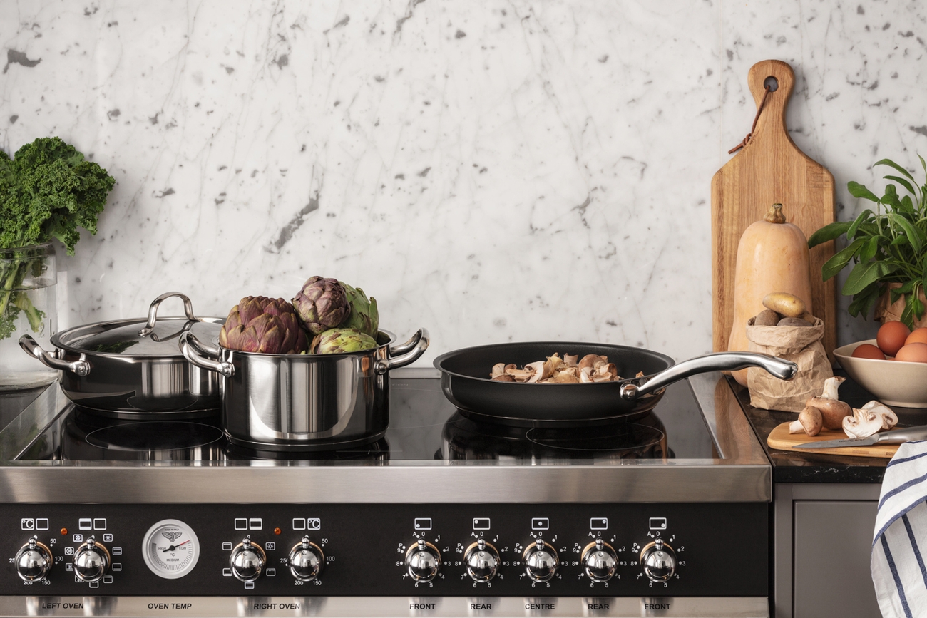 Et kjøkken med en komfyr, stekeovn og kjeler og panner på toppen