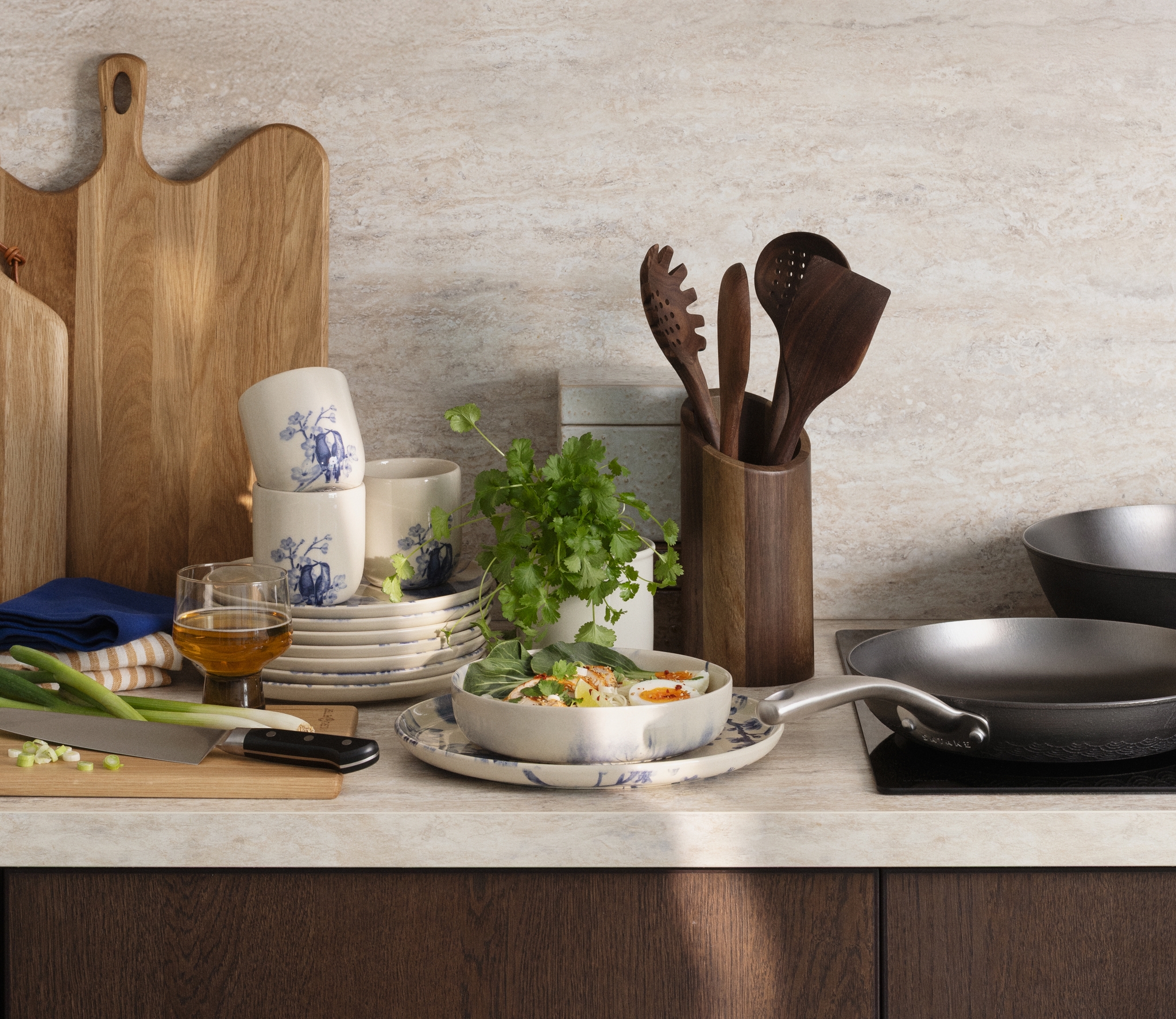 En köksbänk med en färdiglagad måltid, köksredskap, tallrikar och skärbrädor i trä.