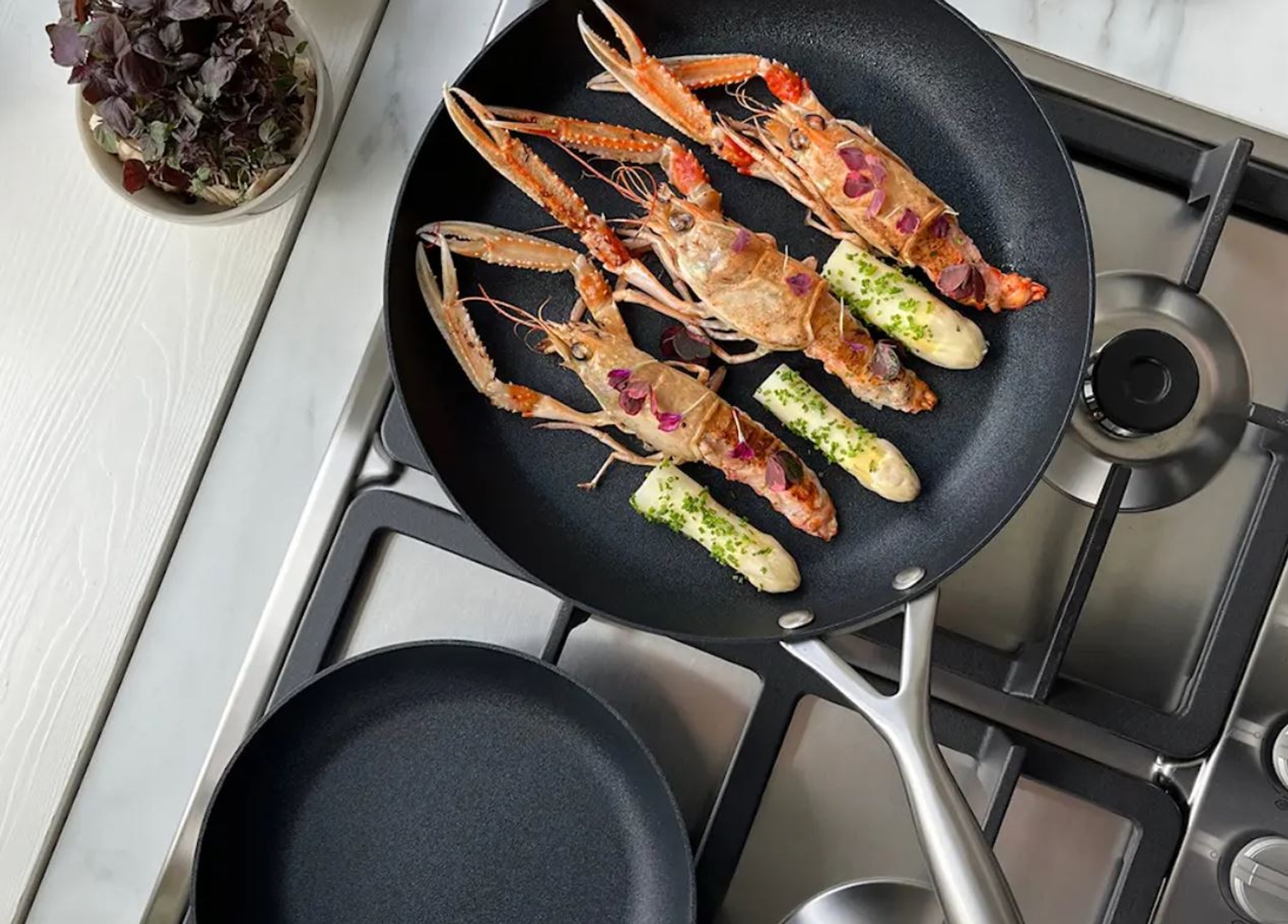 shrimp and asparagus are being cooked in a frying pan on a stove .