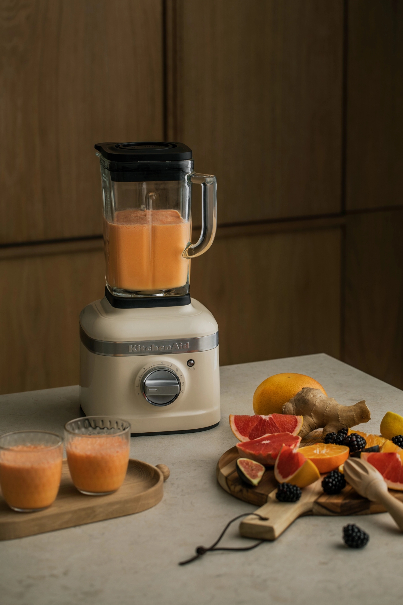 Kitchenaid blender med frisk smoothie i med massevis med frukt ved siden av