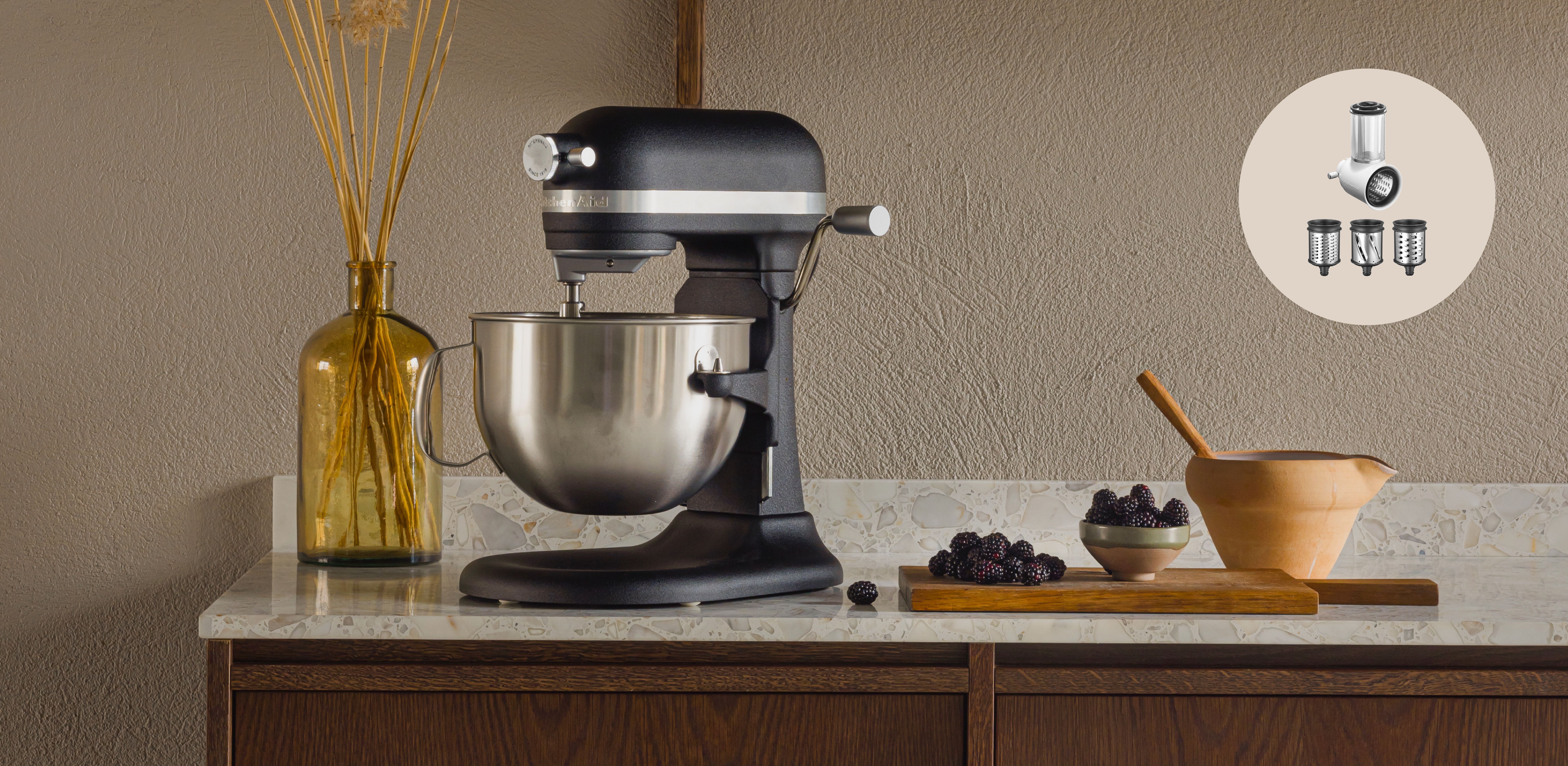 En KitchenAid-mikser står på en benk ved siden av en bolle med bjørnebær