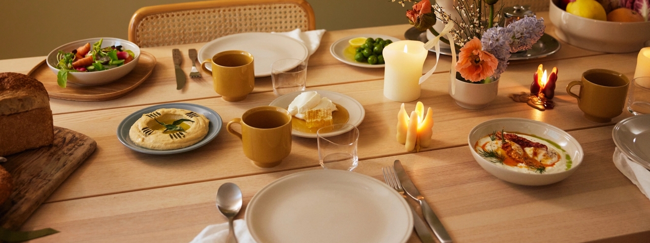 Ett dukat bord i höstens färger med stämningsfulla ljus och porslin i gult och vitt