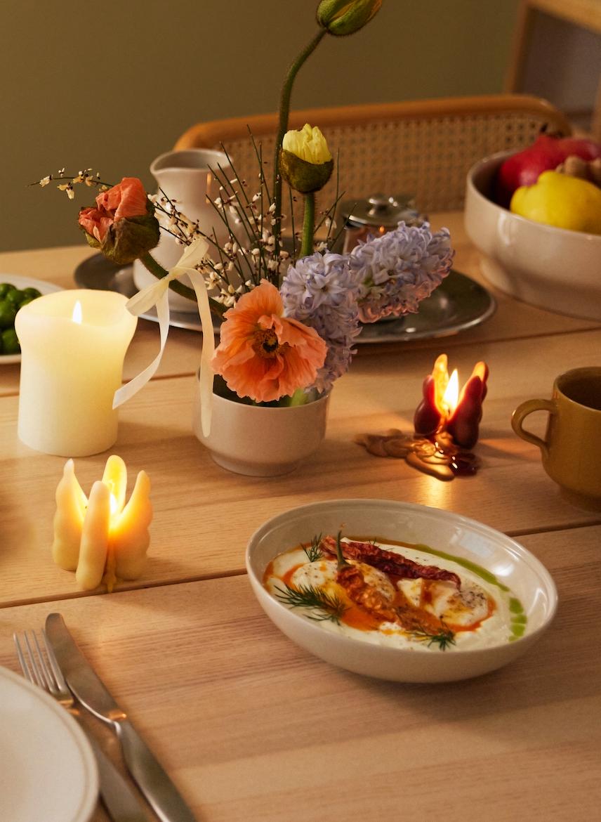 Ett dukat bord i höstens färger med stämningsfulla ljus och porslin i gult och vitt