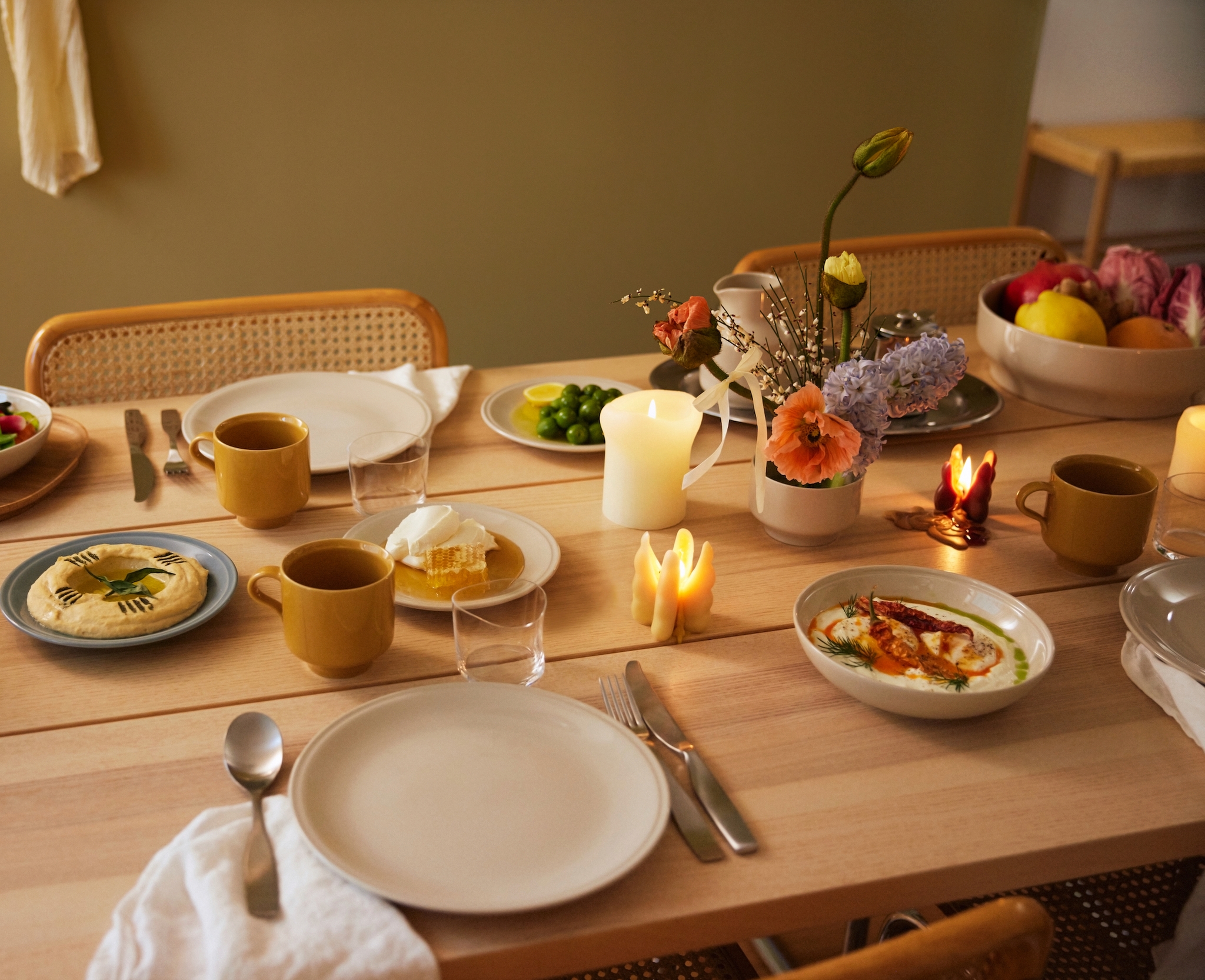 Mysigt dukat matbord med levande ljus, blommor, bröd och färgglada smårätter.