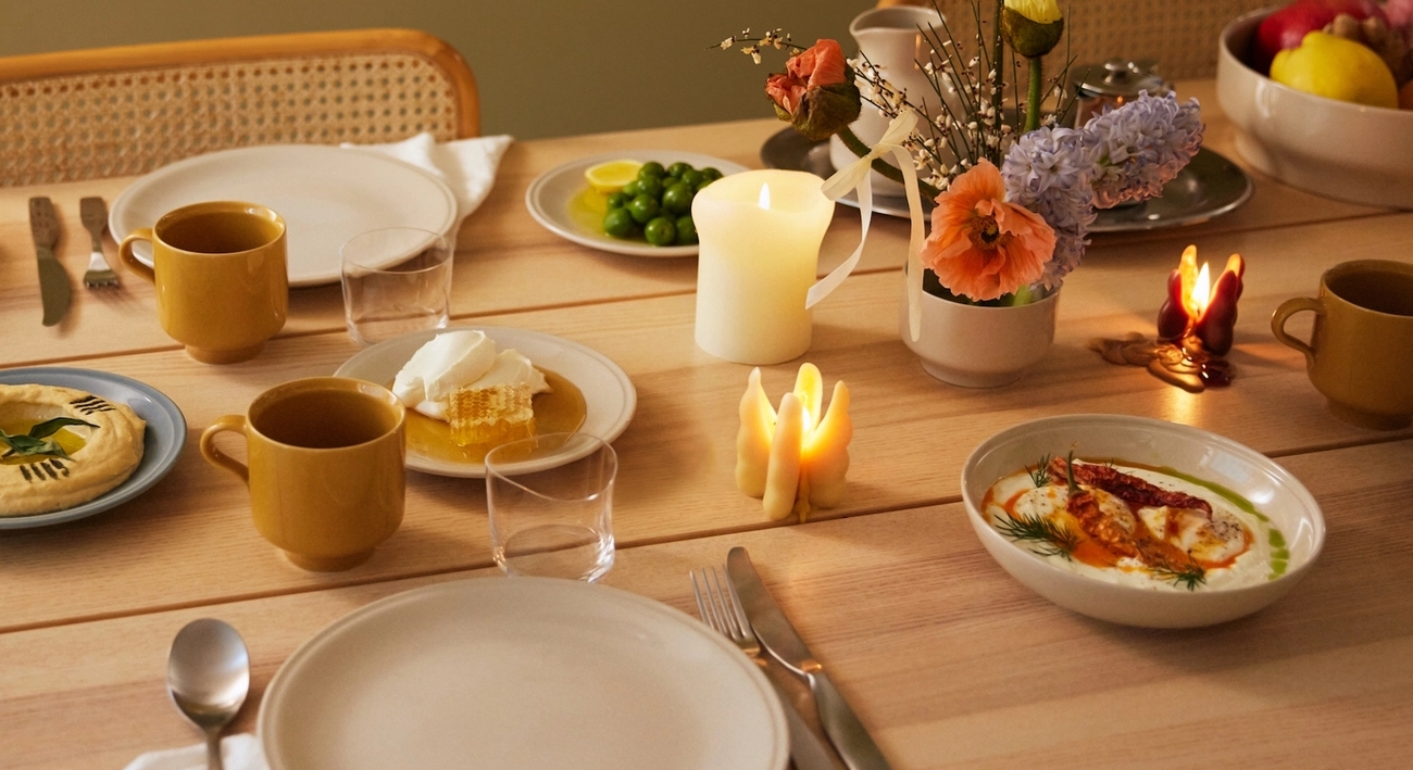 Ett dukat bord i höstens färger med stämningsfulla ljus och porslin i gult och vitt