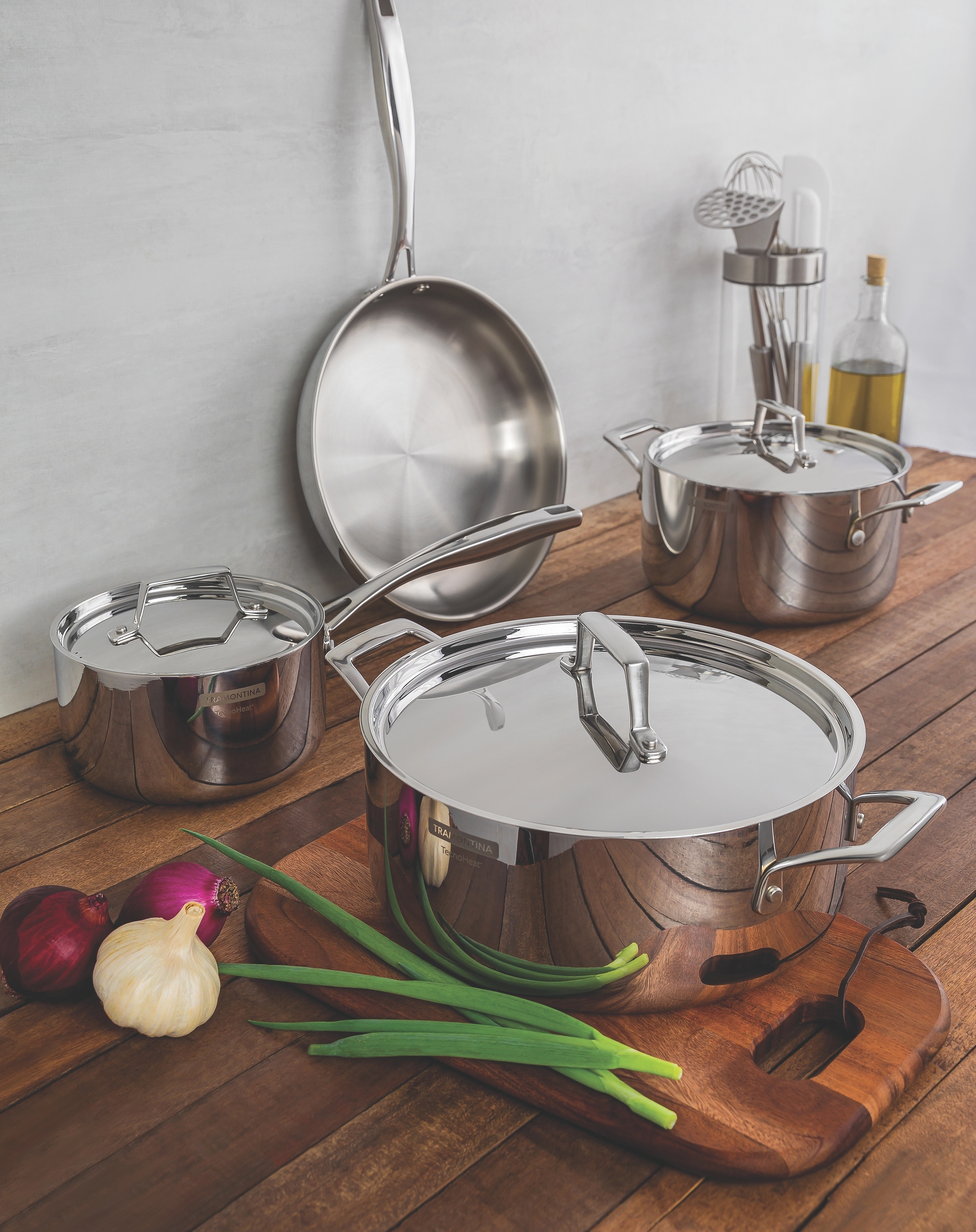 joukko ruostumattomasta teräksestä valmistettuja kattiloita ja pannuja puisella tiskillä