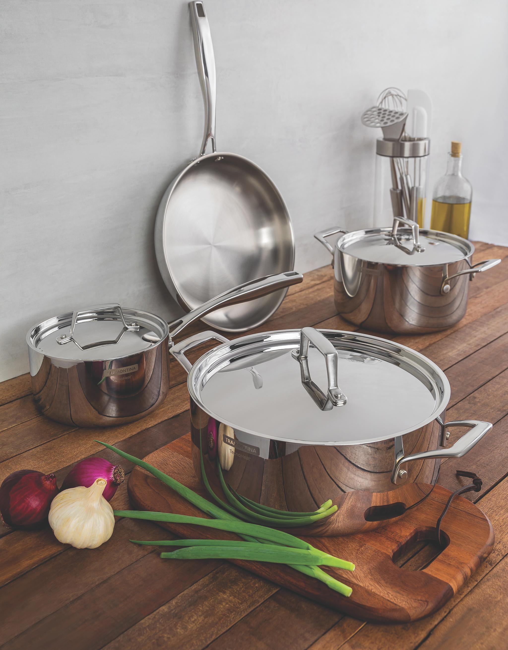 joukko ruostumattomasta teräksestä valmistettuja kattiloita ja pannuja puisella tiskillä