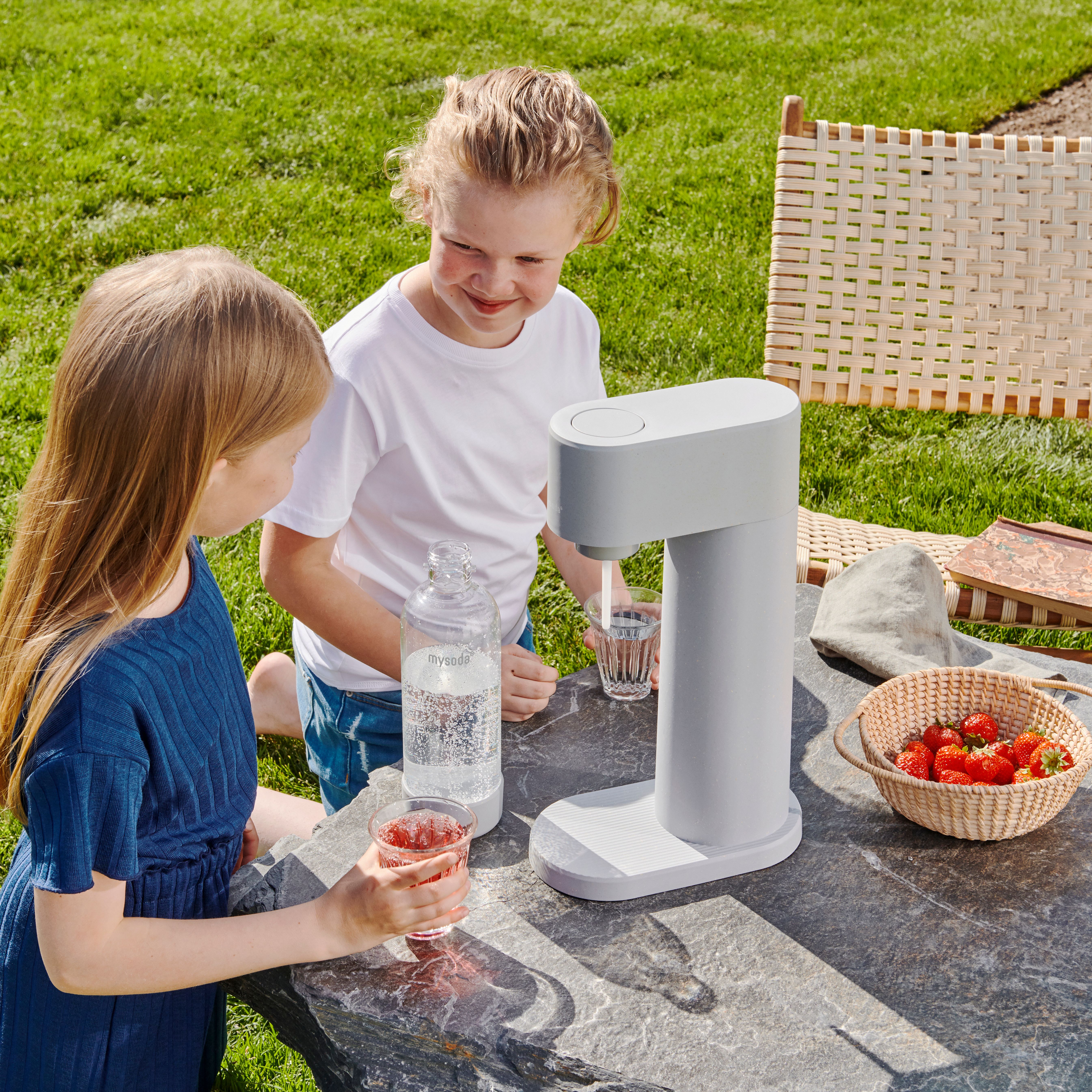 Mysoda woody hiilihapotuslaite ja muovinen pullo ulkona pöydällä 