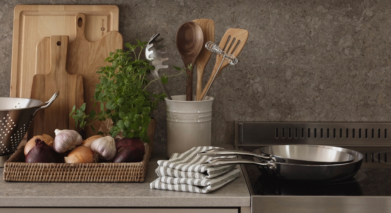 Köksredskap på en köksbänk med en skål med lökar