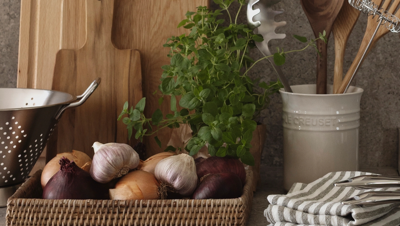 Köksredskap på en köksbänk med en skål med lökar