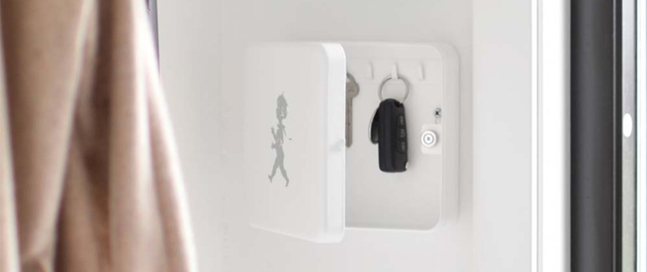 En hvit nøkkelholder på en vegg ved siden av et vindu