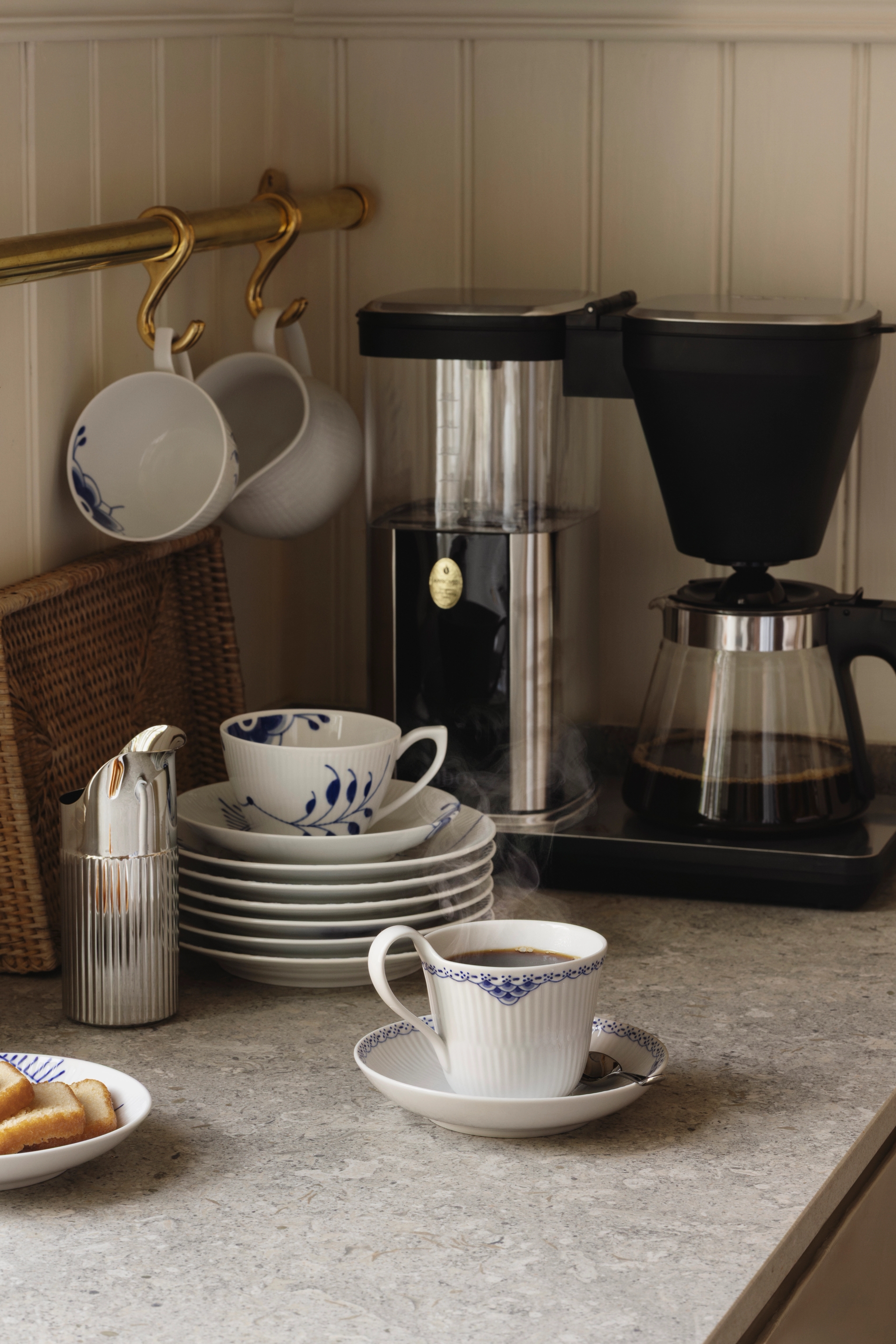  En kaffebryggare står på en bänk bredvid koppar och fat