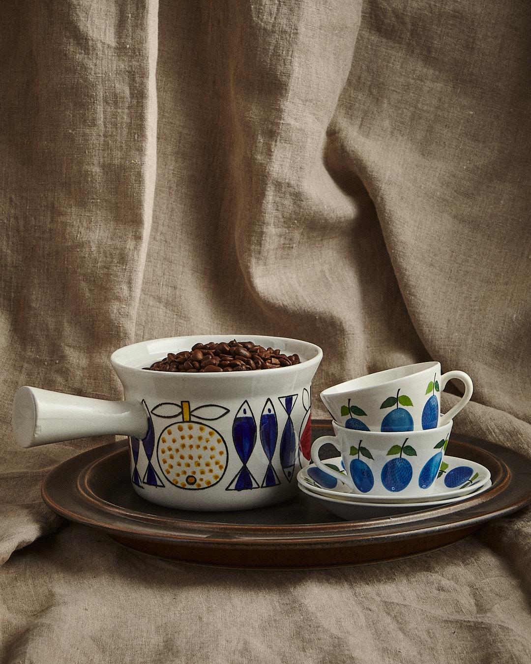 Kaffekoppar och fat med blåbärsmönster på en bricka