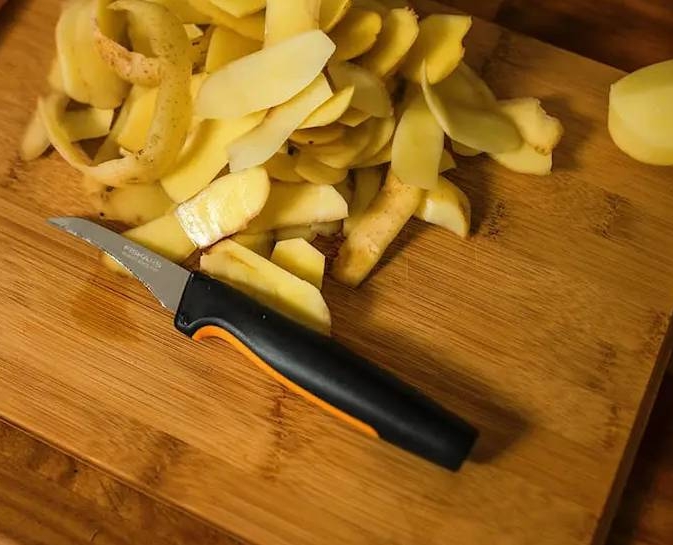fiskars kuorimaveitsi leikkuulaudallatäynnä perunankuoria