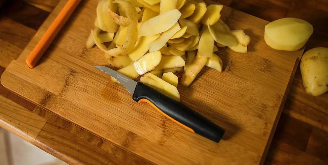 fiskars kuorimaveitsi leikkuulaudallatäynnä perunankuoria
