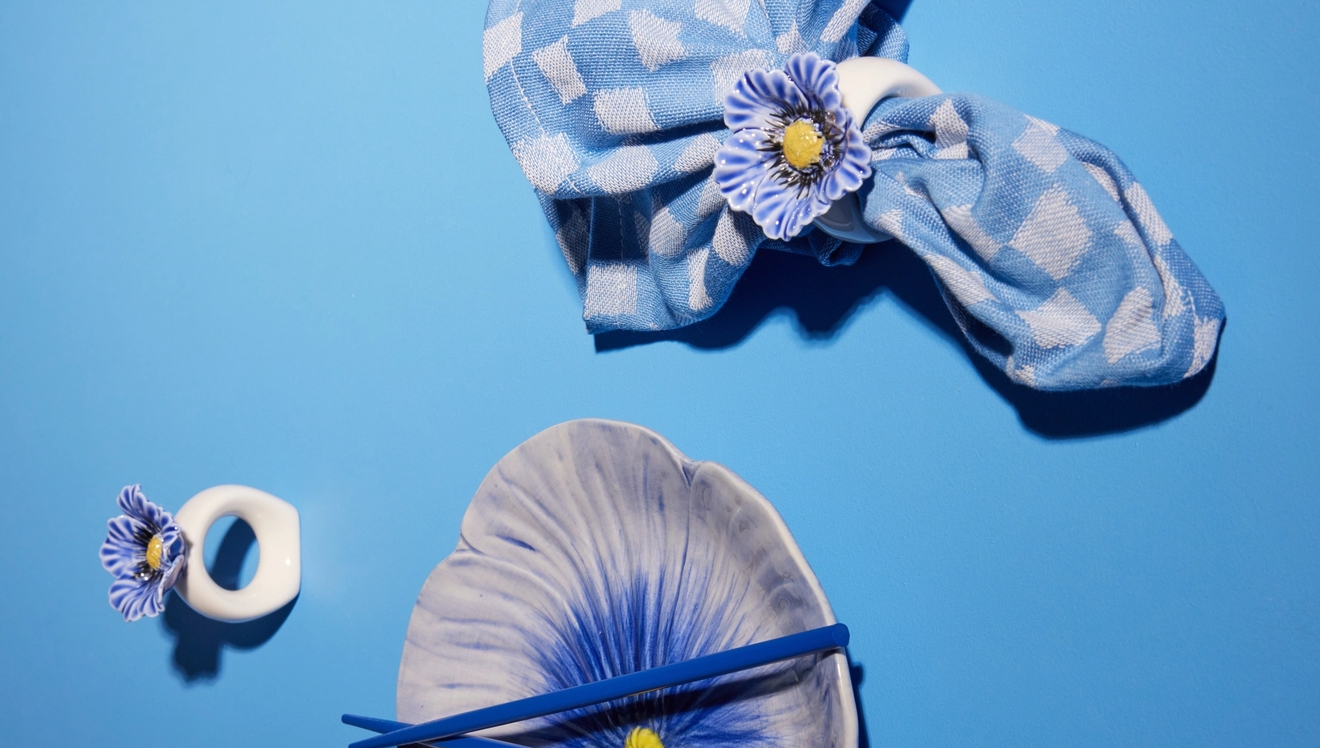 Serviettringer med blå blomst rundt blå og hvitrutet tøyserviett