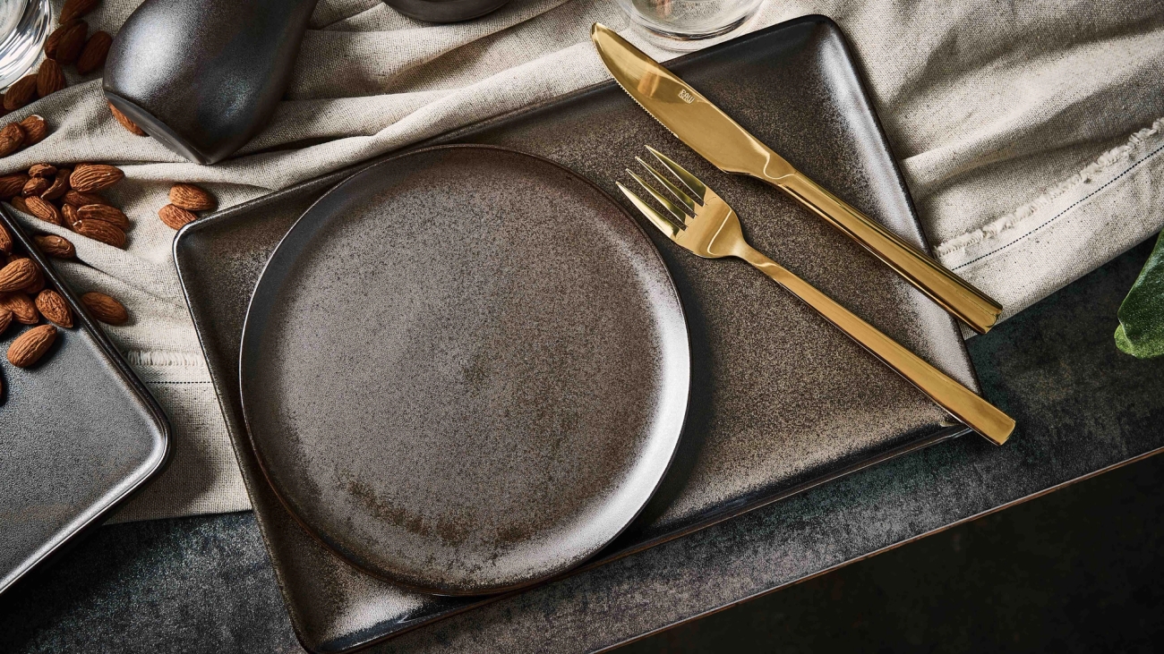 Aida raw Kultaiset haarukka ja veitsi sekä musta lautanen ja tarjotin