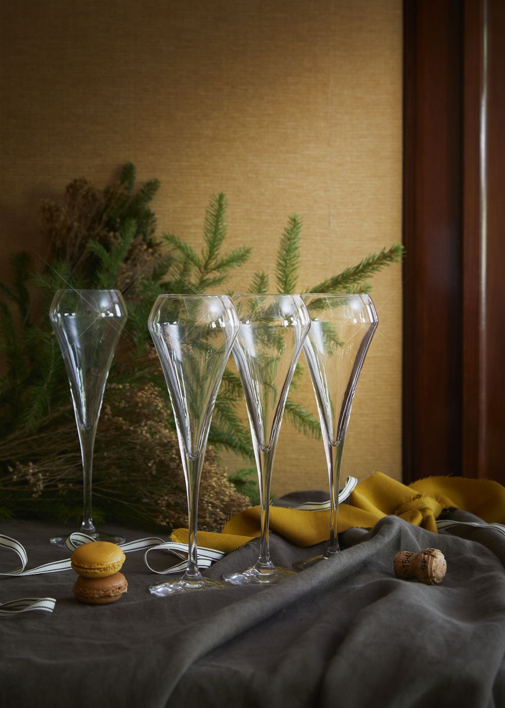 Ett dukat bord med champagneglas, glasskålar och en vas med gula blommor