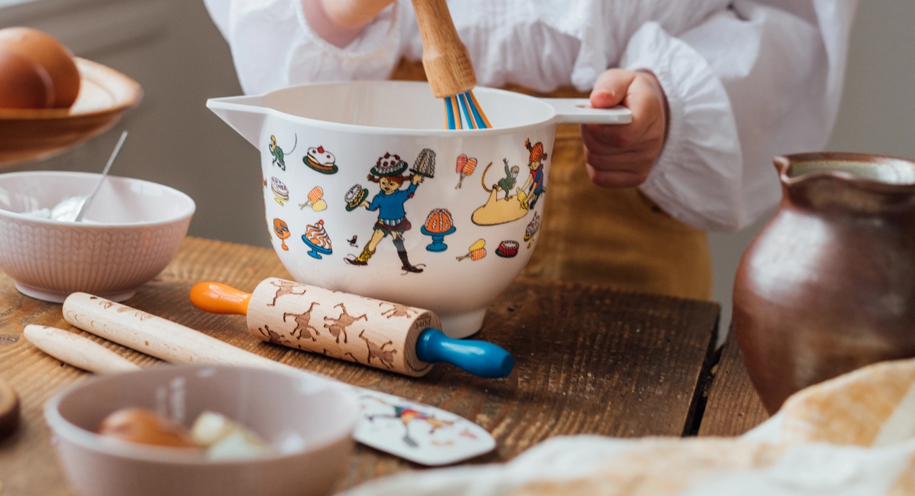 Lasten keittiövälineet - taikinakulho kaulin ja kaavin pöydällä leivonnan aikana