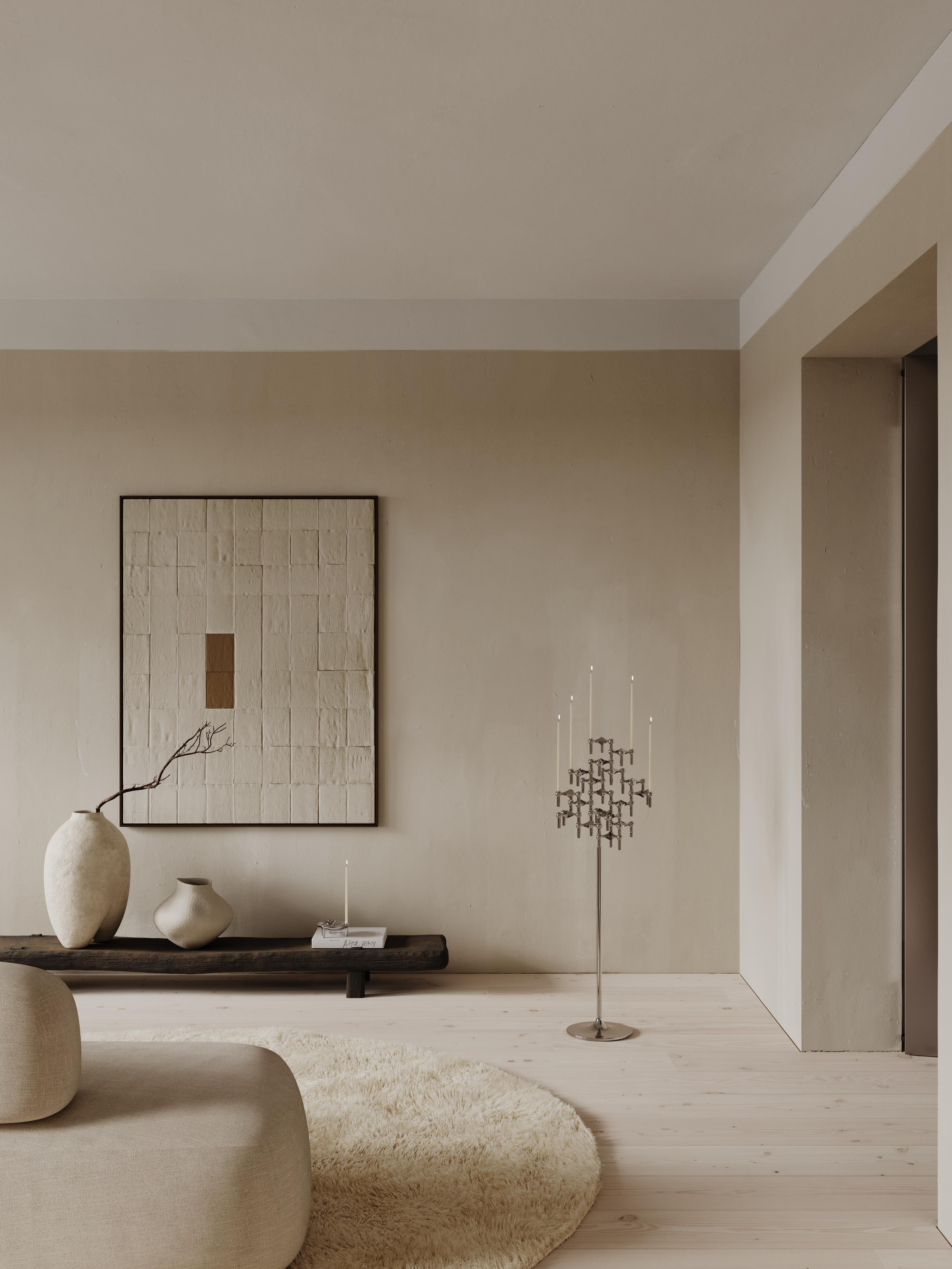 Hög golvljusstake i silver med levande ljus i ett vardagsrum