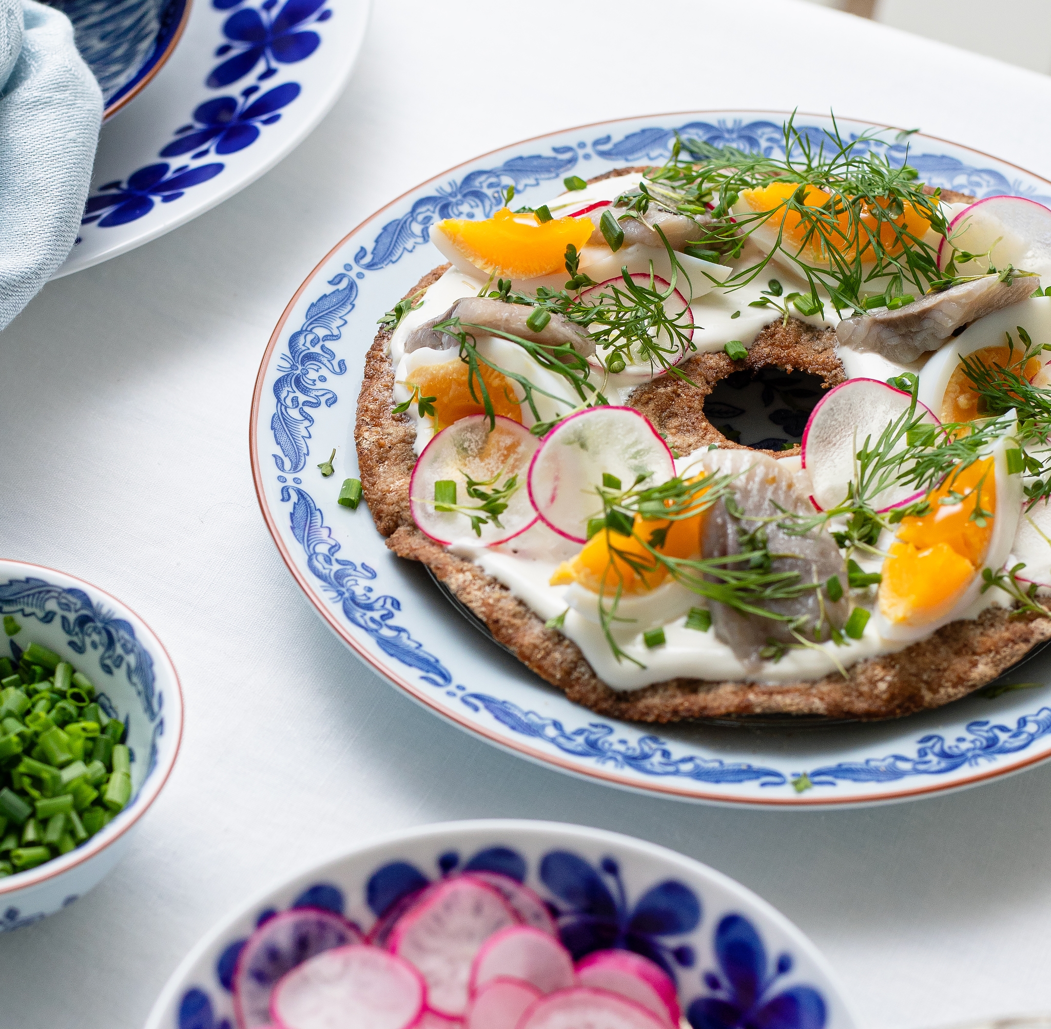 Knäckebröd med vackert upplagd sill, kokt ägg, rädisor och dill på en tallrik
