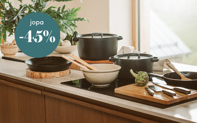 Tyylikkäästi katettu keittiötaso, jossa on mustia kattiloita, paistinpannu ja leikkuulaudat, sekä teksti jopa -45 % alennus.