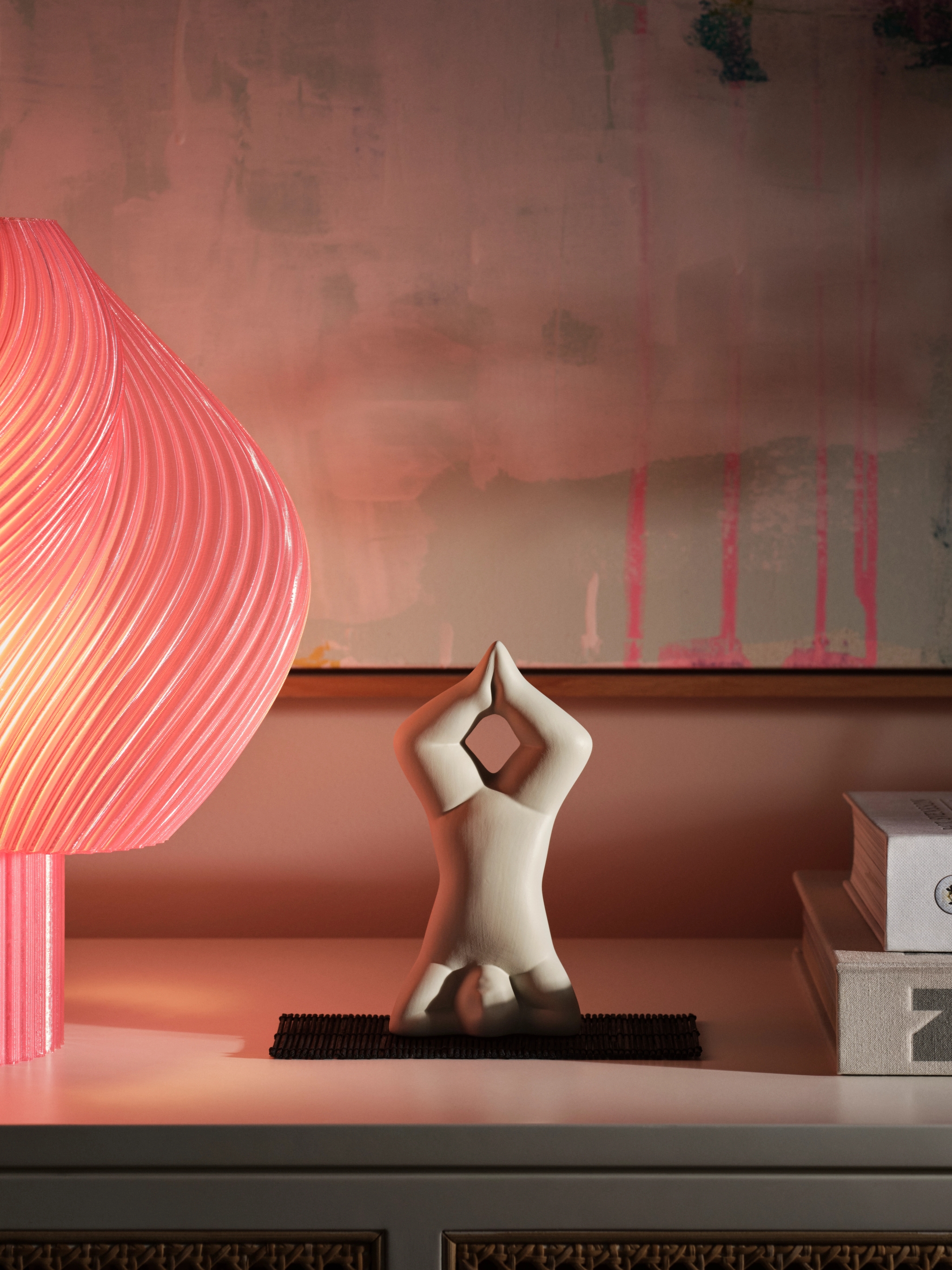 Figuren Yoga av Lisa Larson i färgen ljusgrått som står på huvudet på en hylla med en rosa lampa bredvid