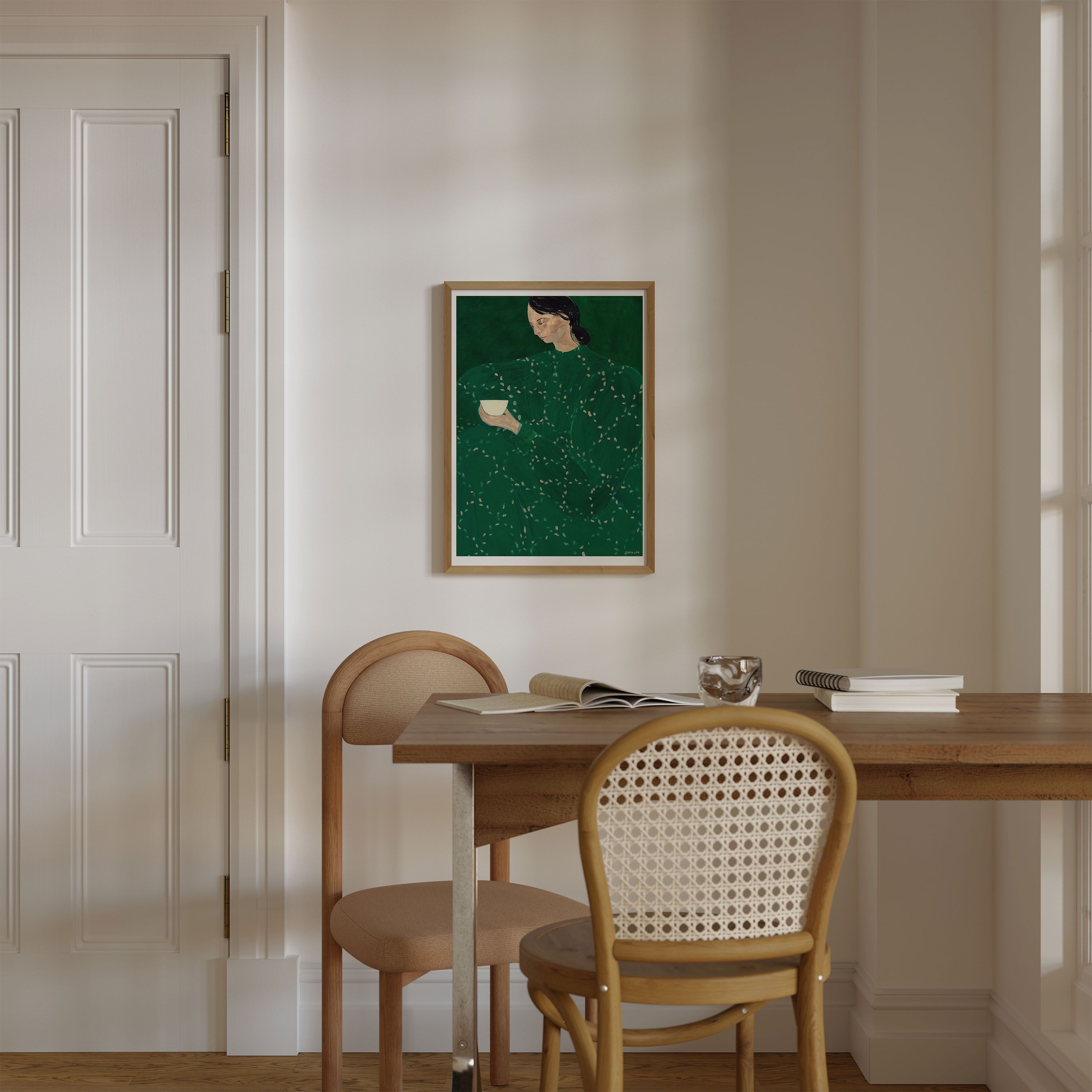 En tavla av en kvinna i grön klänning som hänger på en beige vägg vid ett matbord