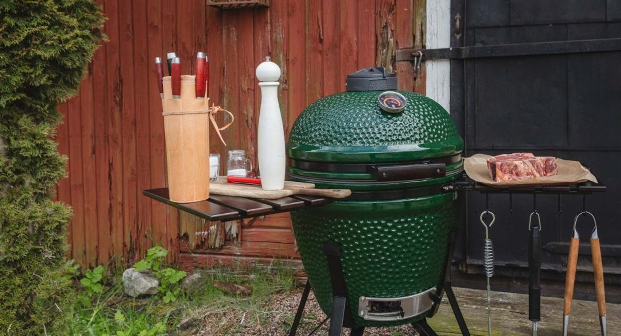 Kamadogrill grön uppställd med kött samt salt och peppar vid sidan 