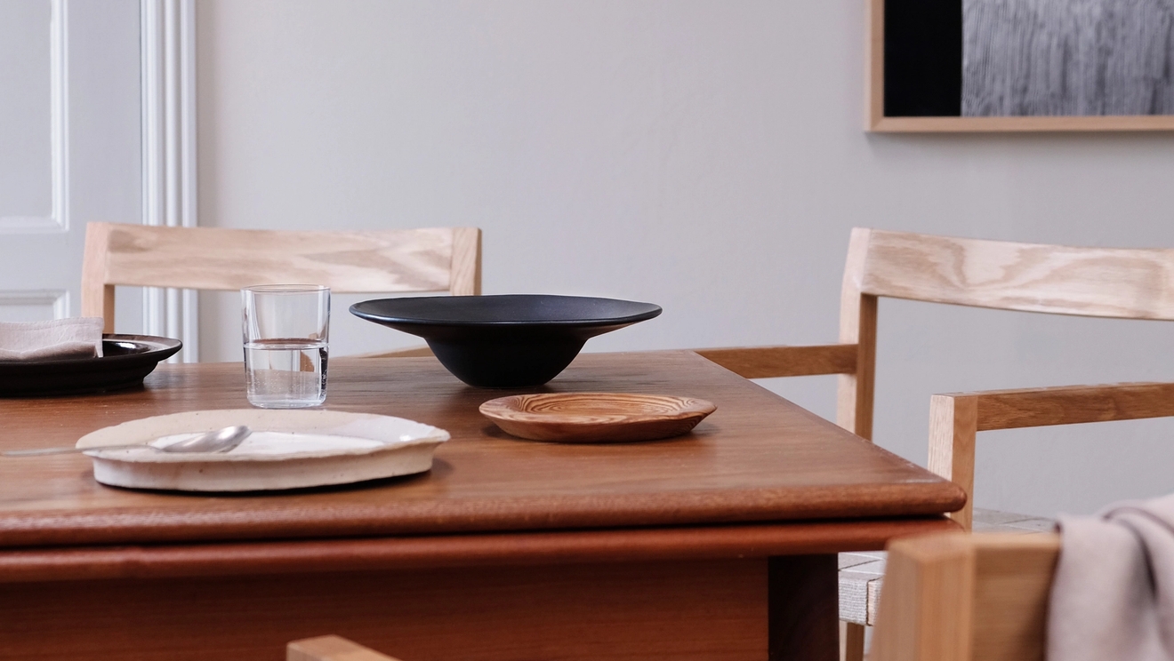 Matplats med bord och stolar i mörkt trä som är dukat med trenigt porslin