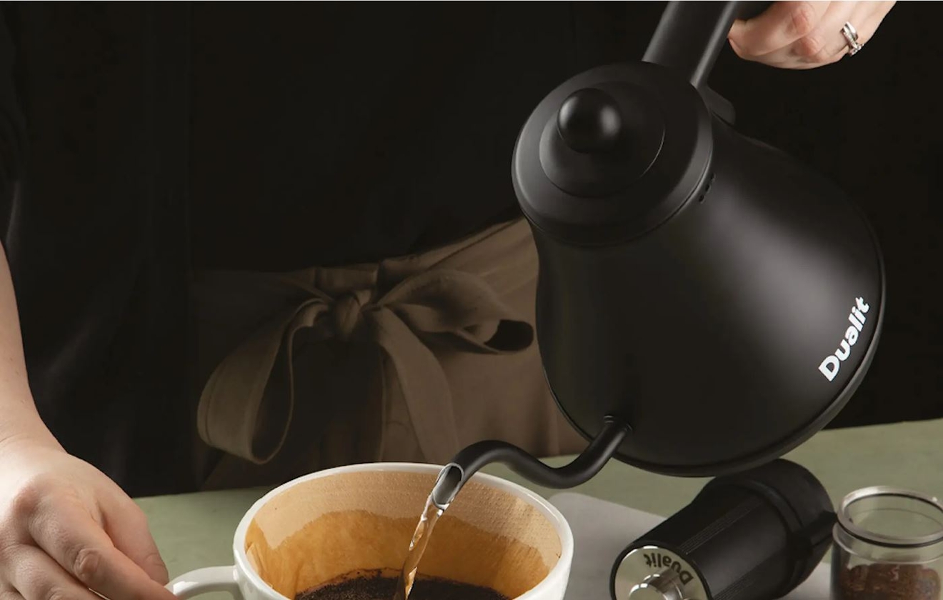 Dualit vedenkeitin värissä musta josta kaadetaan kuumaa vettä valkoiseen mukiin