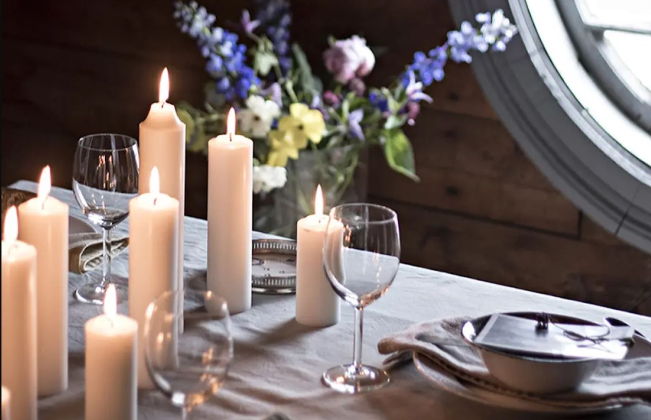 Liljeholmens blockljus på ett uppdukat bord med en lila sommarbukett