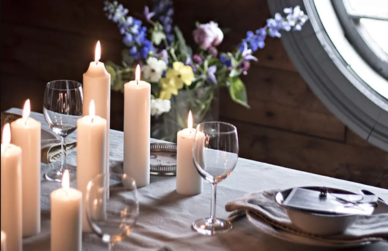 Liljeholmens blockljus på ett uppdukat bord med en lila sommarbukett