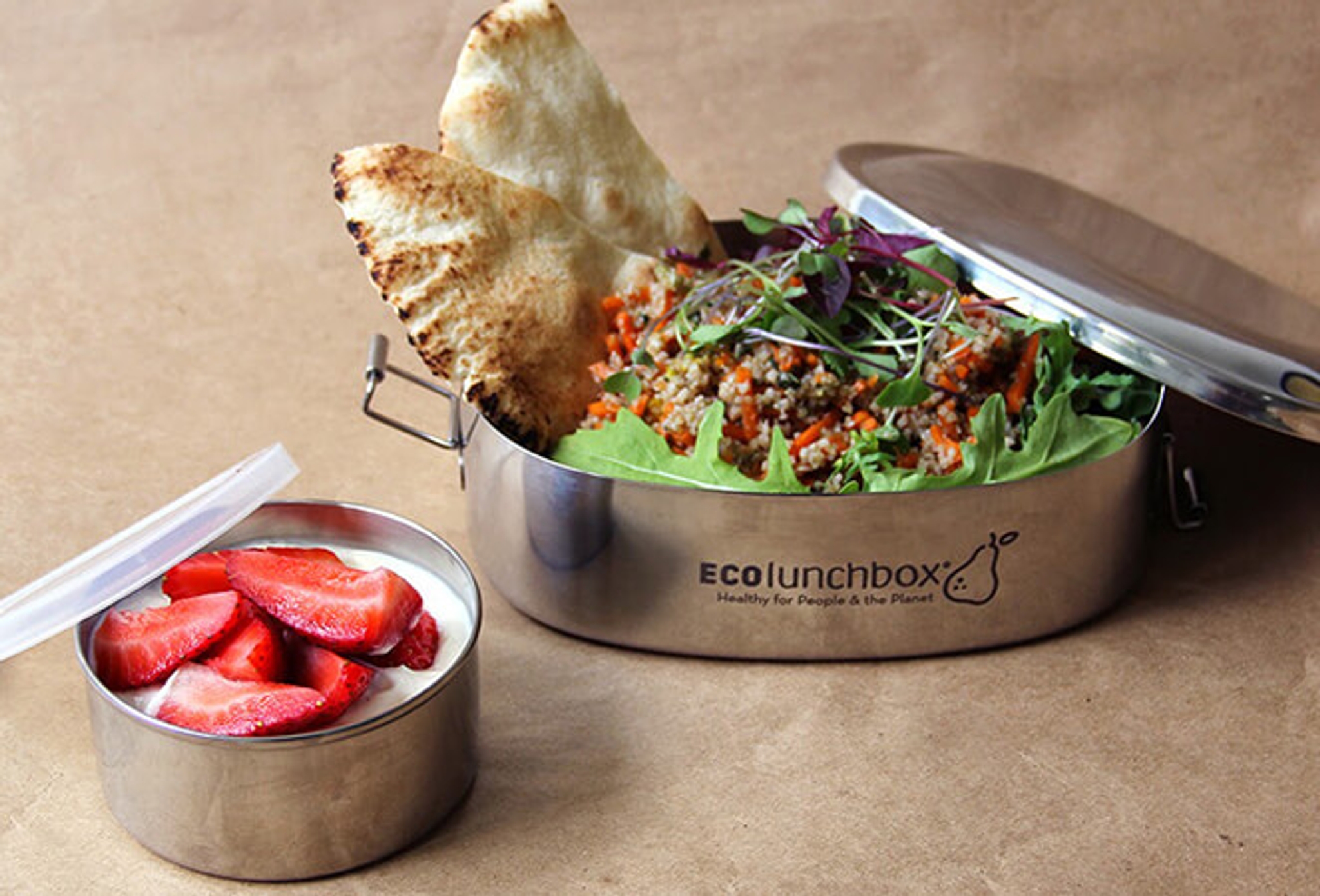 Avoin ECO Lunchbox -eväsrasia, täytetty salaatilla, jyvillä ja naan-leivällä, sekä pieni rasia jogurttia ja mansikoita.