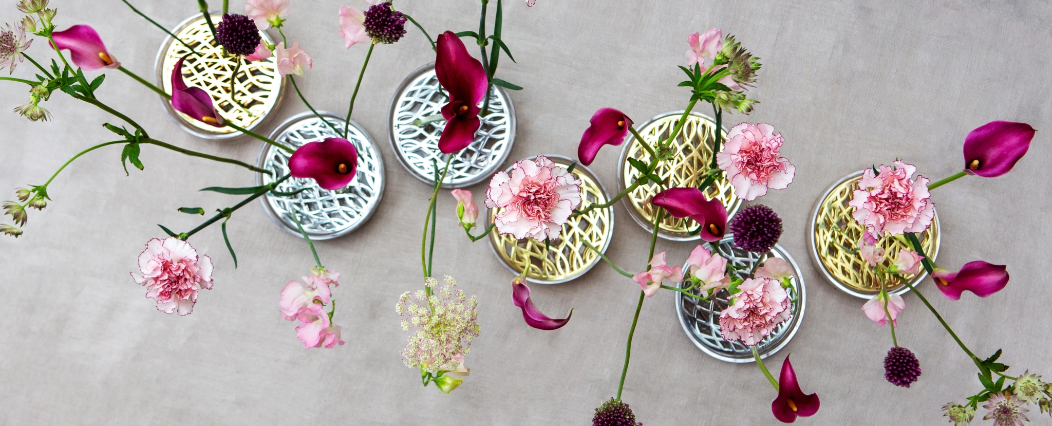 Rosa och lila blommor i mässing- och silvervaser från Klong
