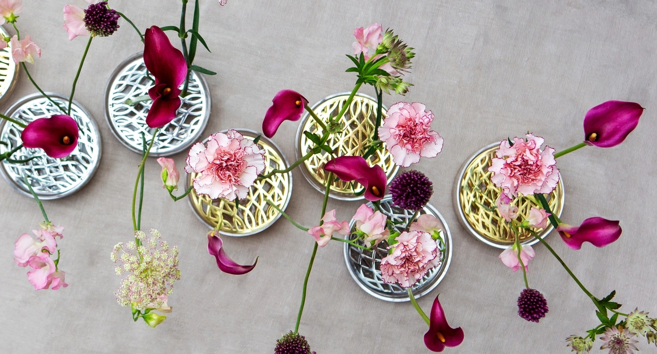 Rosa och lila blommor i mässing- och silvervaser från Klong