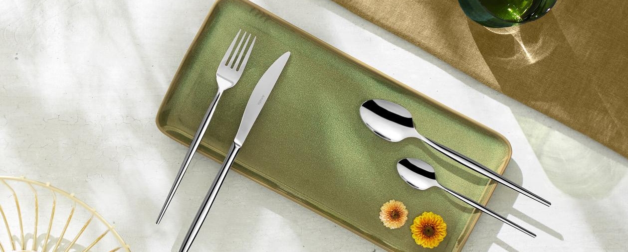 Amefa bestick i silver på en grön rektangulär tallrik på ett bord