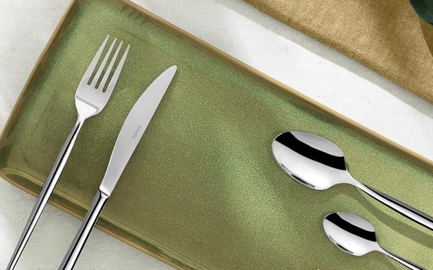 Amefa bestick i silver på en grön rektangulär tallrik på ett bord