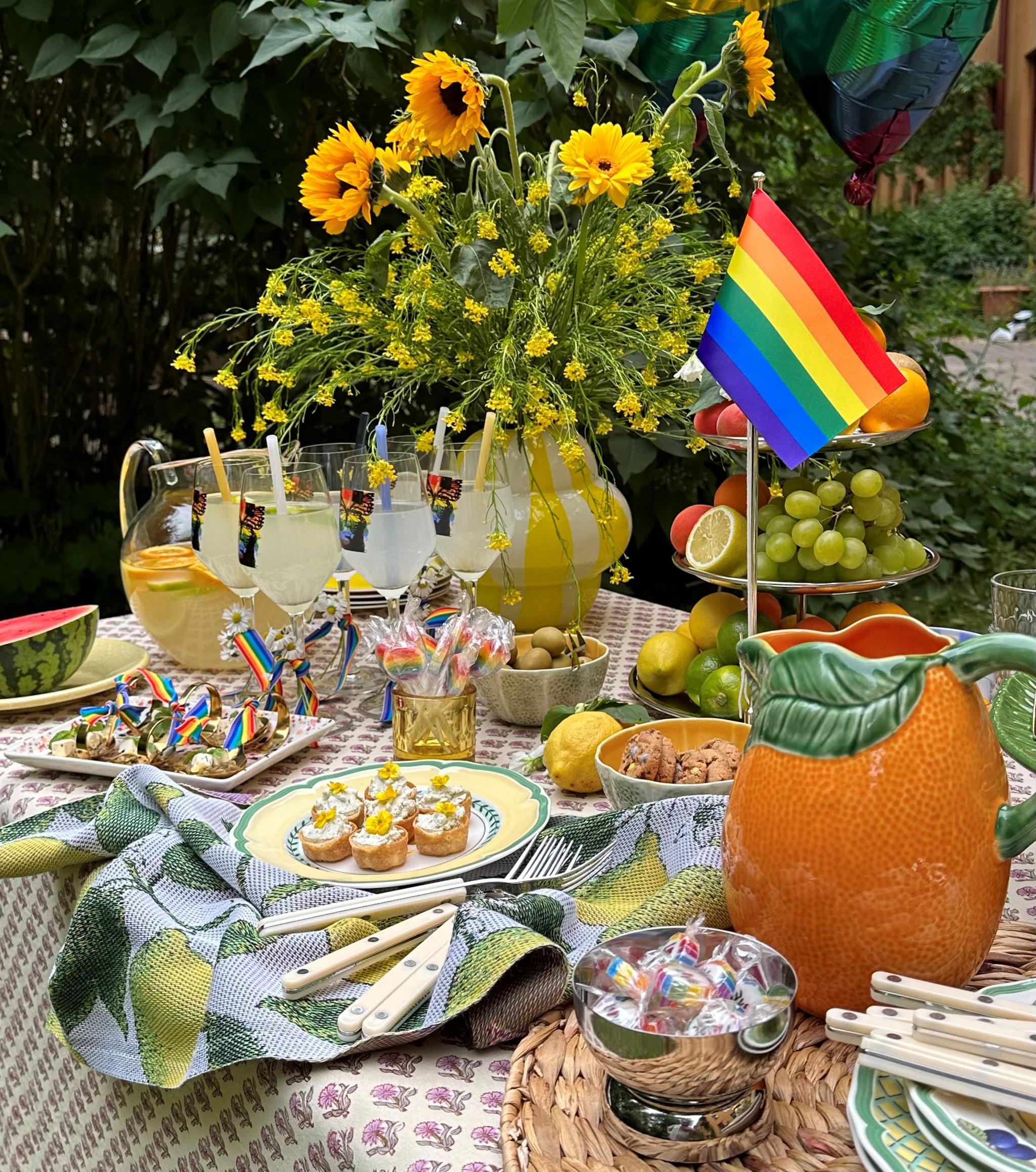 Festlgt dukat bord med Pride-flagga i regnbågens färger och fika