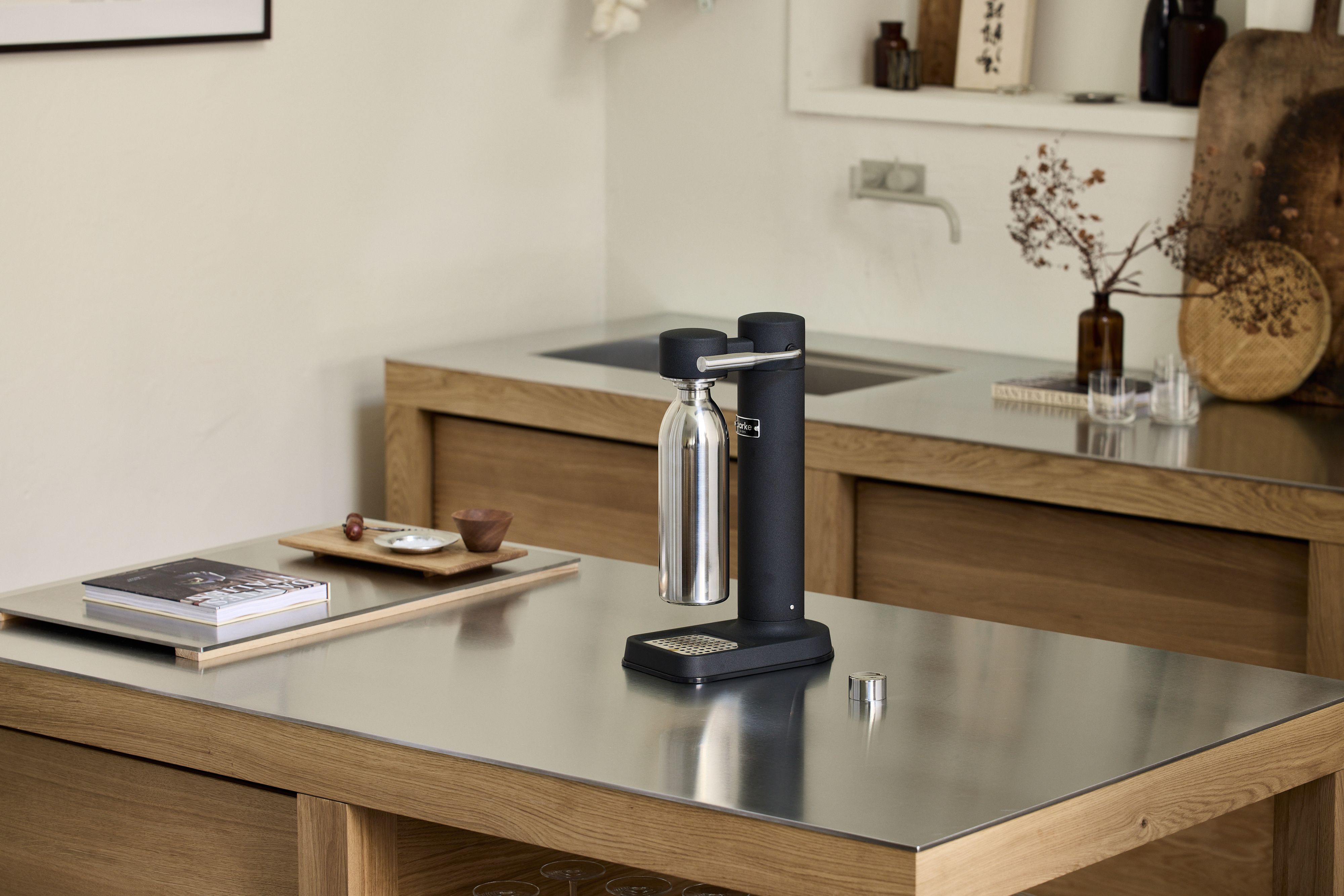 En svart kolsyremaskin från Aarke med en stålflaska står på en köksbänk i ett modernt skandinaviskt kök