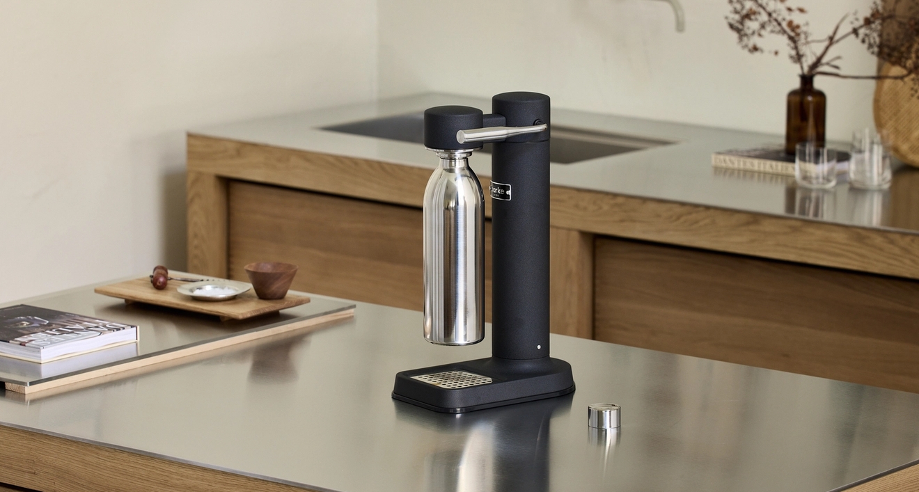 En svart kolsyremaskin från Aarke med en stålflaska står på en köksbänk i ett modernt skandinaviskt kök