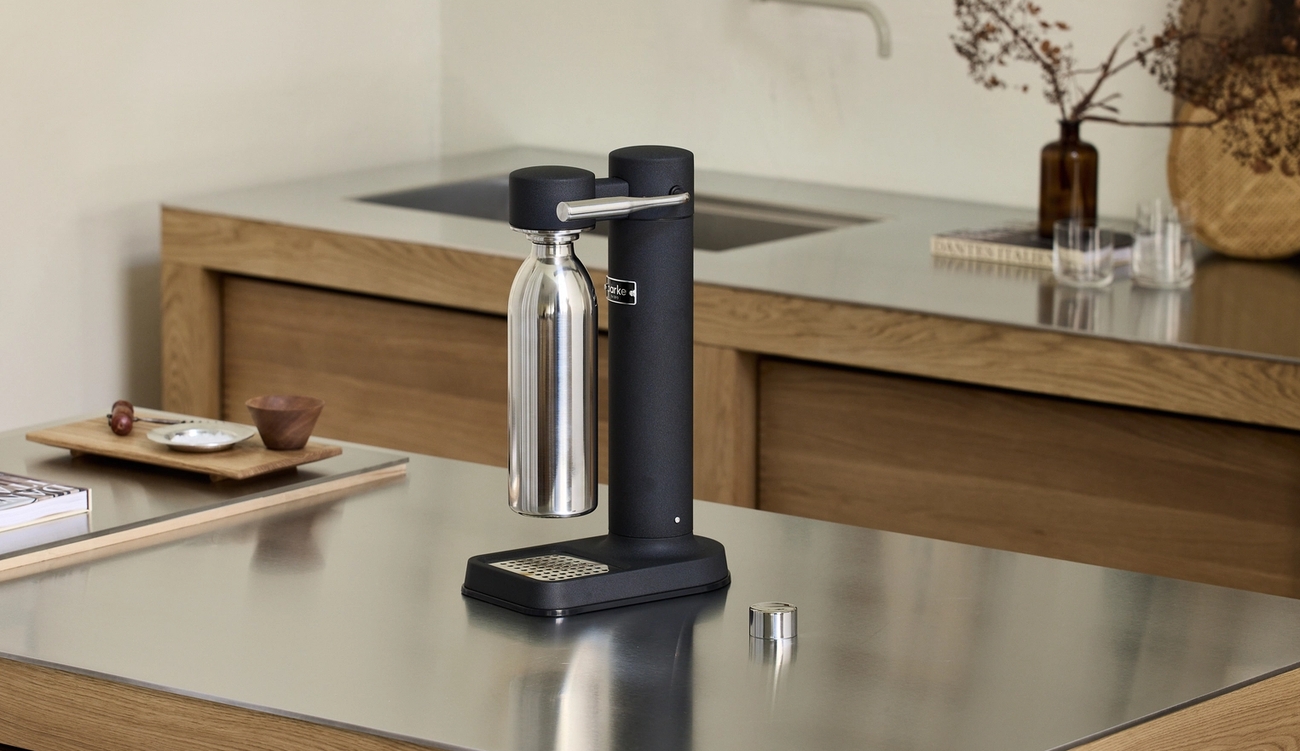 En svart kolsyremaskin från Aarke med en stålflaska står på en köksbänk i ett modernt skandinaviskt kök